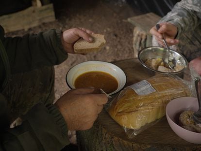 Two Ukrainian soldiers eat at their base on the Zaporizhzhia front, in October 2023.