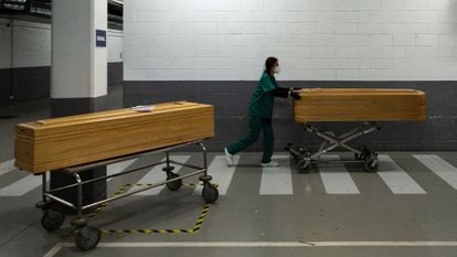 A worker at a funeral home moving the coffin of a coronavirus victim.