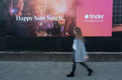 A woman walks past an ad for the Tinder dating app.