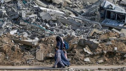 A woman walks with her children past the rubble of a building in Al Nuseirat refugee camp in Gaza.