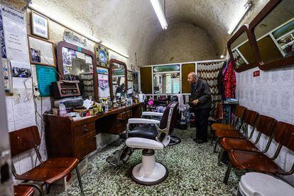 Un peluquero espera clientes en su negocio en el barrio viejo de Jerusalén.