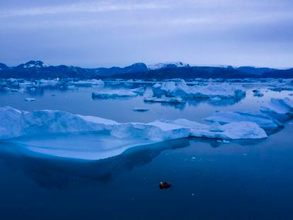 A boat navigates at night next to large icebergs near the town of Kulusuk, in eastern Greenland on Aug. 15, 2019.