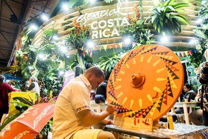 An artisan paints a wooden cartwheel at Costa Rica's stand. The stand, which is covered in plants, pays homage to the country’s ecotourism. Inside, coffee, juices and cotton candy are served.