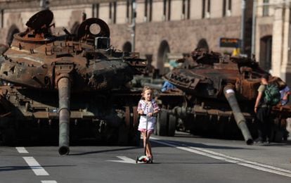 A girl rides a scooter past Russian vehicles on display in central Kyiv during the Independence Day celebration on August 24, 2023.

