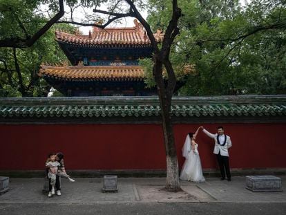A bride and groom pose for a photo outside the Temple of Confucius, in Beijing, on September 26, 2023.