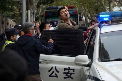 A protestor is pushed into a police car during the November 27 rally in Shanghai.