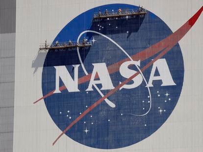 Workers on scaffolding repaint the NASA logo near the top of the Vehicle Assembly Building at the Kennedy Space Center in Cape Canaveral