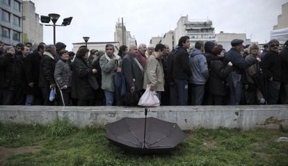 People wait in line to receive food from Athens City Hall. 