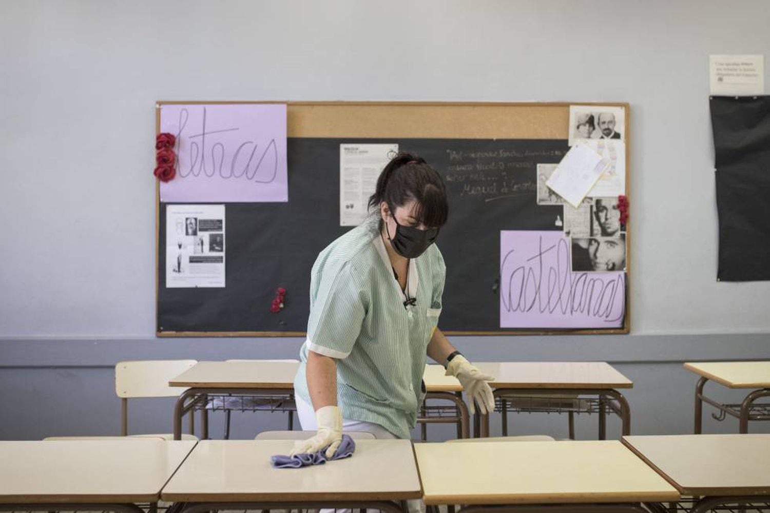 A cleaner wearing a mask prepares a classroom in Barcelona.