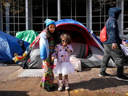Migrant sisters pose wearing their Halloween costumes next to a small migrant tent community. Nov. 1, 2023, near a Northside police station in Chicago.