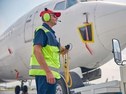 An airport worker wearing earmuffs to protect his ears from airplane noise.