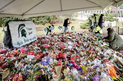 People work to remove flowers from the memorial at the Rock in honor of three students killed at Michigan State University on March 2, 2023, in East Lansing, Michigan.