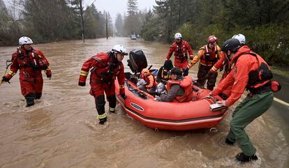 Sonoma County Fire District firefighters and a sheriff's deputy pull people in the back of the boat in Guerneville, California, on March 14, 2023.