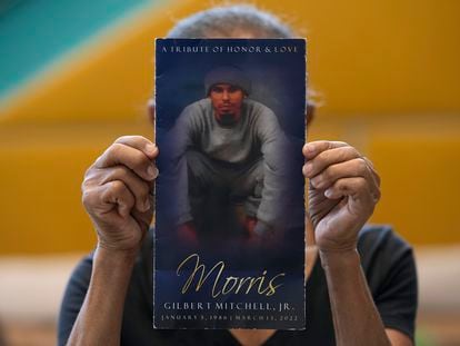 Natalia Mitchell, holds up a program memorializing her son, Morris Mitchell, who was shot to death in March 2022, in Washington, Monday, Oct. 30, 2023.