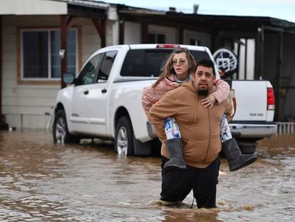 Ryan Orosco, of Brentwood, carries his wife Amanda Orosco, from their flooded home on Bixler Road in Brentwood, Calif., on Monday, Jan. 16, 2023.