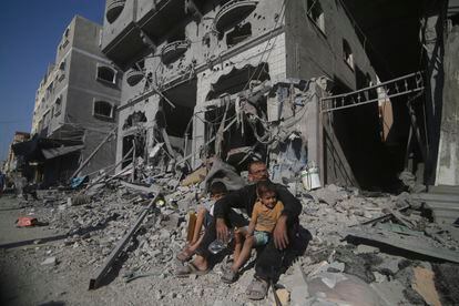 Palestinians sit outside their house following Israeli airstrikes in Rafah refugee camp, southern Gaza Strip, on Thursday, October 12, 2023. 