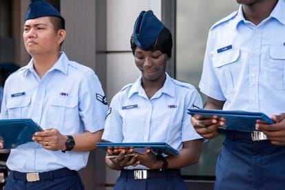Airman 1st Class Joshua Fancisco, from the Philippines, left, Airman 1st Class D'elbrah Assamoi, from Cote D'Ivoire, center, and Airman 1st Class Jordan Flash, from Jamaica, looks at their U.S. Certificate of Citizenship after signing it following the Basic Military Training Coin Ceremony on April 26, 2023, at Joint Base San Antonio-Lackland, Texas.