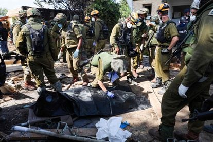 Israeli soldiers prepare to remove the body of a compatriot, killed during an attack by the Palestinian militants, in Kfar Aza, south of Israel bordering Gaza Strip, on October 10, 2023. 