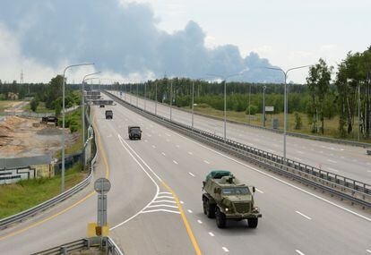 A military column of Wagner private mercenary group drives along M-4 highway, which links the capital Moscow with Russia's southern cities, with smoke from a burning fuel tank at an oil depot seen in the background, near Voronezh, Russia, June 24, 2023.